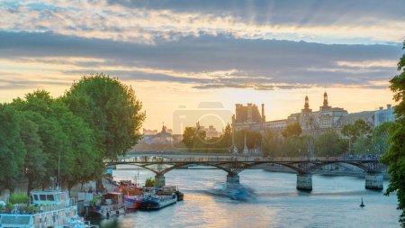 Téléchargez les photos : Ciel orange vue rapprochée sur le soleil derrière le toit près du Pont des Arts à Paris au coucher du soleil timelapse du Pont Neuf, France. Navire sur la Seine près de la place du Vert-Galant - en image libre de droit
