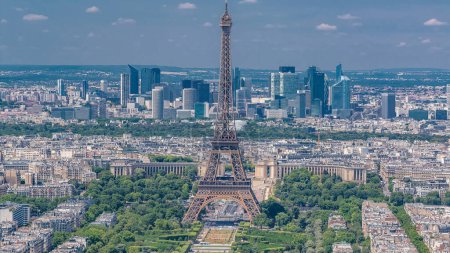 Téléchargez les photos : Vue aérienne depuis la tour Montparnasse avec la tour Eiffel avec des personnes sur un belvédère et le quartier de la Défense sur fond timelapse à Paris, France. Vue de dessus de la terrasse d'observation à la journée ensoleillée d'été. - en image libre de droit