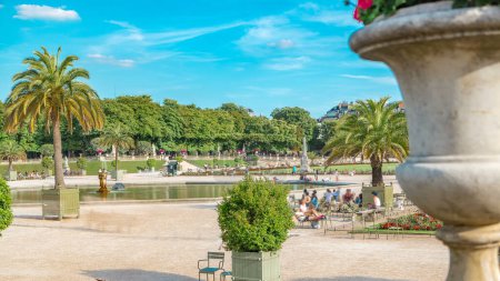 Téléchargez les photos : La belle vue sur les jardins du Luxembourg timelapse avec fontaine à Paris, France. Des gens qui se promènent. Ciel bleu nuageux le jour d'été. - en image libre de droit