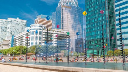 Téléchargez les photos : Gratte-ciel de La Défense timelapse - Moderne quartier d'affaires et résidentiel et fontaine. Arbres verts, ciel nuageux bleu au soleil jour d'été réfléchi par la surface du verre. Paris, France - en image libre de droit