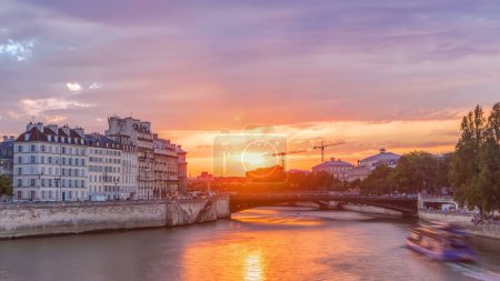 Photo for Le Pont D'Arcole bridge at sunset with people and boats timelapse, Paris, France, Europe. Colorful sky at summer day with reflection on river Seine. Construction with cranes on a background - Royalty Free Image