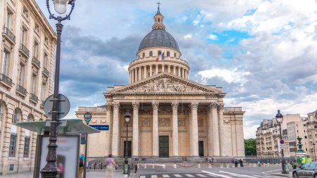 Téléchargez les photos : Panthéon national bâtiment timelapse, vue de face avec drapeau français sur le dessus et rue avec les gens. Trafic routier, temps nuageux le jour d'été. Paris, France - en image libre de droit