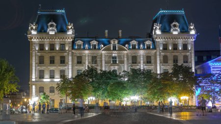 Foto de Parvis Notre Dame noche timelapse - Place Jean-Paul II. Edificio frente a Notre Dame de Paris con iluminación nocturna. Gente caminando por la plaza. París. Francia - Imagen libre de derechos