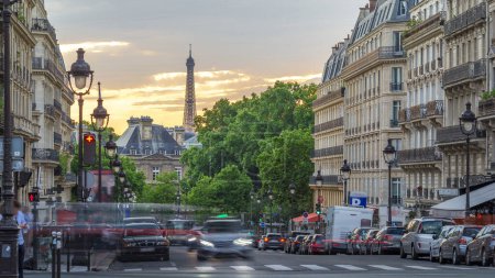 Photo for Sun setting behind a building on a Parisian Soufflot street with traffic and bus stop timelapse with Eiffel tower on background. Cloudy orange sky at summer day - Royalty Free Image