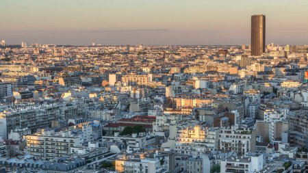 Téléchargez les photos : Panorama aérien au-dessus des toits des maisons dans un timelapse de transition de jour à nuit de Paris. Vue d'ensemble du soir avec visites principales éclairées après le coucher du soleil - en image libre de droit