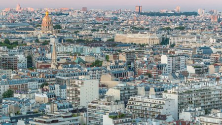 Téléchargez les photos : Panorama aérien au-dessus des toits des maisons dans un timelapse de transition de jour à nuit de Paris. Vue du soir avec les invalides, église et autres sites touristiques illuminés après le coucher du soleil - en image libre de droit
