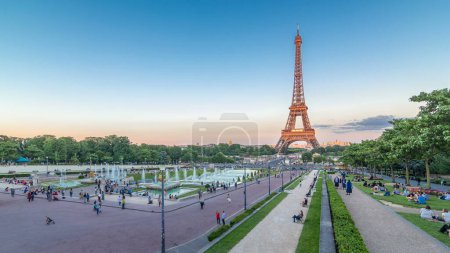 Photo for Sunset view of Eiffel Tower timelapse with fountain in Jardins du Trocadero in Paris, France. Long shadows. People walking around. Eiffel Tower is one of the most iconic landmarks of Paris. - Royalty Free Image