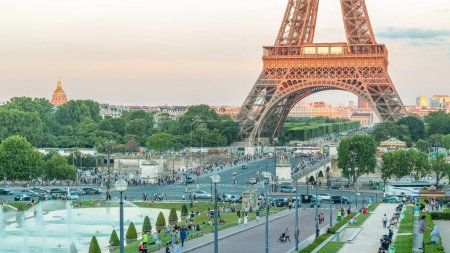 Téléchargez les photos : Coucher de soleil sur la Tour Eiffel timelapse avec fontaine dans les Jardins du Trocadéro à Paris, France. Des gens qui se promènent. La Tour Eiffel est l'un des monuments les plus emblématiques de Paris. Ombres longues. - en image libre de droit
