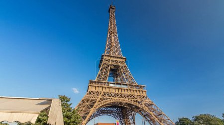 Foto de La torre Eiffel con luz cálida durante la puesta del sol hiperlapso timelapse. Cielo azul en la tarde soleada. Es uno de los hitos más reconocibles del mundo. - Imagen libre de derechos