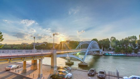 Téléchargez les photos : Passerelle Passarelle Debilly au coucher du soleil timelapse avec des touristes observant la Seine et les bateaux naviguant sur l'eau. Ciel bleu nuageux le jour d'été - en image libre de droit