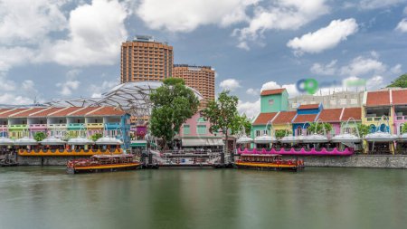 Foto de Barcos turísticos atracando en Clarke Quay puerto timelapse hiperlapso con casas de colores. Clarke Quay es un muelle histórico a orillas del río en Singapur, dentro del área de planificación del río Singapur.. - Imagen libre de derechos