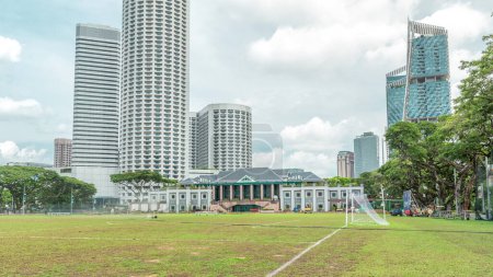 Foto de Skyline con Singapore Recreation Club y rascacielos en segundo plano hiperlapso timelapse. Césped verde y nubes en el cielo - Imagen libre de derechos
