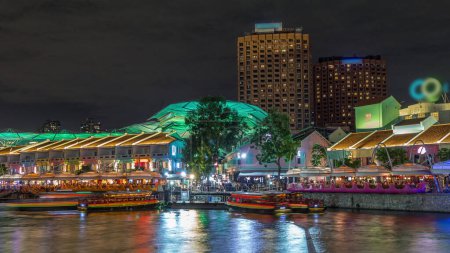 Téléchargez les photos : Bateaux touristiques accostage à Clarke Quay habour timelapse de nuit avec des maisons éclairées. Clarke Quay est un quai historique au bord de la rivière à Singapour, situé dans la zone de planification de la rivière Singapour
. - en image libre de droit