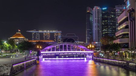 Photo for Skyline of Singapore financial district and Marina bay behind Elgin Bridge and the Singapore River night timelapse hyperlapse. Parliament building on the left side - Royalty Free Image