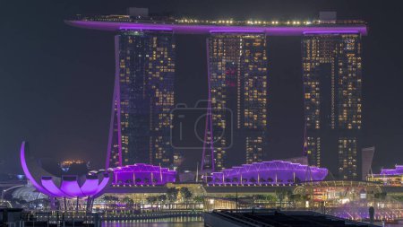 Téléchargez les photos : Cinquante-cinq étages de haut Marina Bay Sands Hotel domine l'horizon de Marina Bay à Singapour la nuit aérienne timelapse. Fontaines avec lumière laser montrer - en image libre de droit