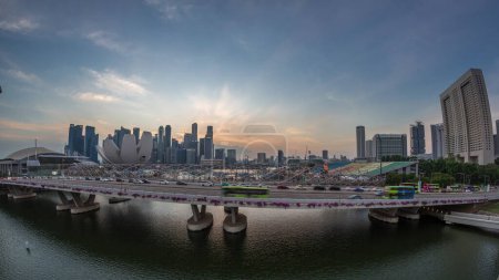 Téléchargez les photos : Vue aérienne sur le pont Helix et Bayfront Avenue avec la circulation de jour à la nuit transition à Marina Bay d'en haut avec gratte-ciel skyline sur un fond, Singapour. Stade flottant sur la droite - en image libre de droit