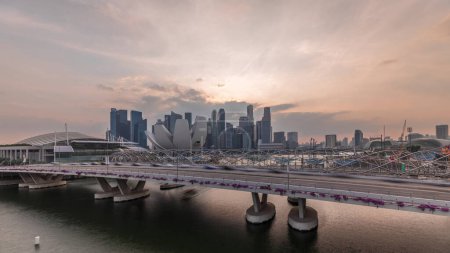 Foto de Vista aérea de la puesta de sol sobre el puente Helix y la avenida Bayfront con timelapse tráfico en Marina Bay desde arriba con rascacielos skyline en un fondo, Singapur - Imagen libre de derechos