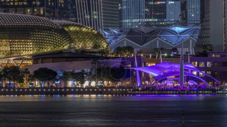 Téléchargez les photos : Les théâtres de l'Esplanade sur la baie de Singapour au crépuscule, avec une belle réflexion dans l'eau nuit timelapse. Tente éclairée avec des personnes - en image libre de droit