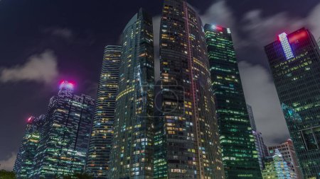 Foto de Mirando hacia arriba la perspectiva de los rascacielos de negocios modernos de vidrio y vista al cielo paisaje de edificio comercial en el centro de la ciudad timelapse hiperlapso. Torres con ventanas brillantes en Singapur - Imagen libre de derechos