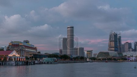 Photo for City skyline with skyscrapers and Esplanade Theatres on the Bay in Singapore at dusk, with beautiful reflection in water day to night transition timelapse. Boats floating on water - Royalty Free Image