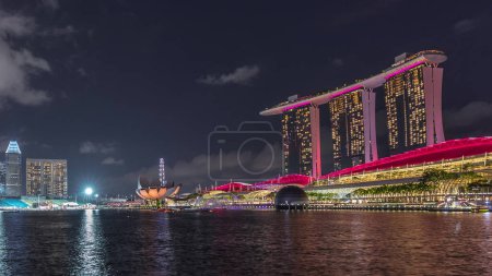 Photo for Beautiful laser and musical fountain show at the Marina Bay Sands waterfront in Singapore night timelapse. Crowd of viewers watching behind of it. Boats floating around - Royalty Free Image