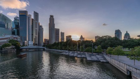 Téléchargez les photos : Les gratte-ciel de Singapour s'alignent avec le pont Anderson blanc et quelques tours du quartier financier près du parc de l'esplanade de jour comme de nuit. Quelques feuillages verts des deux côtés. - en image libre de droit