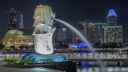 Téléchargez les photos : Merlion fontaine et Singapour skyline nuit. Théâtre d'esplanade et gratte-ciel sur fond. Merlion est une créature imaginaire avec la tête d'un lion et le corps d'un poisson, symbole de Singapour. - en image libre de droit