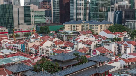 Téléchargez les photos : Le temple de la relique dentaire de Bouddha à Singapour Chinatown timelapse aérien, avec l'horizon de la ville en arrière-plan. Le temple avec des gratte-ciel et des tours. Vieilles maisons aux toits rouges - en image libre de droit