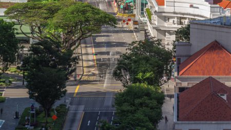 Photo for Traffic with cars on a street and urban scene in the central district of Singapore aerial timelapse. North Bridge road with green trees around - Royalty Free Image