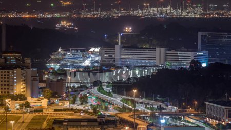 Téléchargez les photos : Singapour terminal de croisière de nuit aérienne qui gère et exploite des ferries et des croisières. Un énorme croisement à l'avant et des cargos flottant sur un fond. Vue depuis le belvédère - en image libre de droit