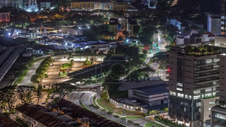 Téléchargez les photos : Vue aérienne de la gare routière animée de Singapour la nuit timelapse. Kampong Bahru Bus Interchange avec la circulation dans les rues. Vue de dessus depuis le belvédère - en image libre de droit