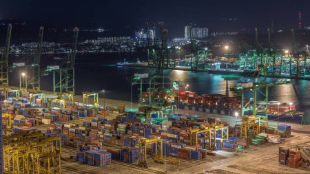 Téléchargez les photos : Port commercial de Singapour timelapse de nuit. Vue panoramique du port de fret asiatique le plus achalandé avec des centaines de navires chargeant des marchandises d'exportation et d'importation et des milliers de conteneurs dans le port - en image libre de droit