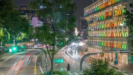 Téléchargez les photos : Éclairé Old Hill Street Police Station bâtiment historique à Singapour timelapse aérien de nuit. Bâtiment de style néoclassique avec des fenêtres colorées. Gratte-ciel sur fond - en image libre de droit