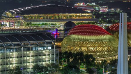 Photo for Beautiful laser and musical fountain show at the Marina Bay Sands waterfront in Singapore aerial night timelapse. Esplanade theatre illuminated roof. Boats floating around - Royalty Free Image