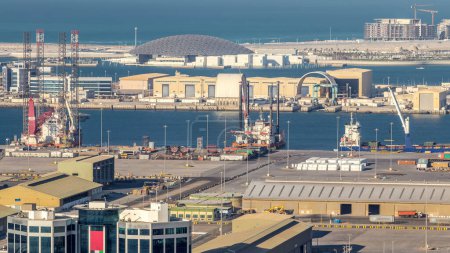 Photo for Big cargo ship at industrial port timelapse aerial view from above at evening in Abu Dhabi. Museum on background - Royalty Free Image