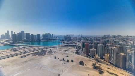 Luftaufnahme des Stadtzentrums von Abu Dhabi von oben im Zeitraffer während des ganzen Tages bis zum Sonnenuntergang mit Schatten von Wolkenkratzern, die sich sehr schnell bewegen.