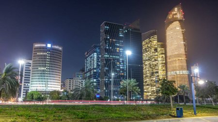 Téléchargez les photos : Skyscrapers in Abu Dhabi Skyline at night timelapse, Émirats arabes unis. Vue de Corniche avec des tours modernes éclairées et la circulation dans la rue - en image libre de droit