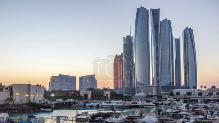 Téléchargez les photos : Al Bateen marina Abu Dhabi de jour comme de nuit timelapse après le coucher du soleil avec des bateaux et des gratte-ciel modernes éclairés sur fond - en image libre de droit