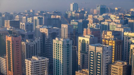 Photo for Skylines under the thick fog at the street timelapse of Abu Dhabi at morning, the biggest city of United Arab Emirates. Aerial view of skyscrapers from above after sunrise - Royalty Free Image