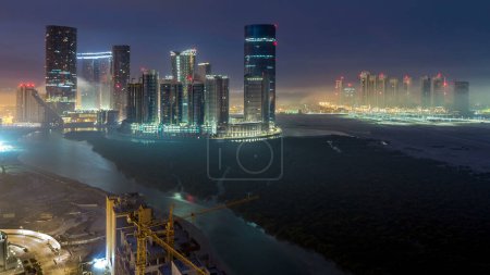Photo for Skyscrapers on Al Reem in Abu Dhabi timelapse during sunrise from above. Aerial cityscape panorama from Al Reem Island at morning with fog. Sun reflected on glass surface - Royalty Free Image