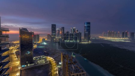 Photo for Skyscrapers on Al Reem in Abu Dhabi timelapse during sunrise from above. Aerial cityscape from Al Reem Island at morning with fog. Sun reflected on glass surface - Royalty Free Image