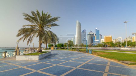 Téléchargez les photos : Corniche boulevard plage parc le long de la côte à Abu Dhabi timelapse hyperlapse avec des gratte-ciel sur fond. Les paumes sur le côté. Ciel bleu au soleil - en image libre de droit