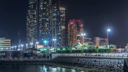 Téléchargez les photos : Les gratte-ciel d'Abu Dhabi illuminés la nuit avec les bâtiments Etihad Towers timelapse avec des fenêtres rougeoyantes. Émirats arabes unis - en image libre de droit