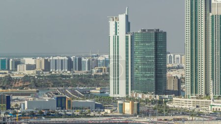 Foto de Edificios en Al Reem y Al Maryah Island en Abu Dhabi timelapse desde arriba. Paisaje urbano aéreo de Al Reem Island por la mañana, mostrando edificios y tráfico en el puente - Imagen libre de derechos