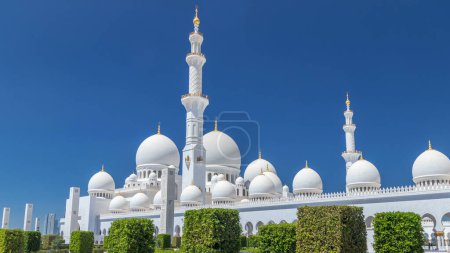 Photo for Sheikh Zayed Grand Mosque timelapse in Abu Dhabi, the capital city of United Arab Emirates. Side view with domes and minarets. Blue sky at sunny day - Royalty Free Image