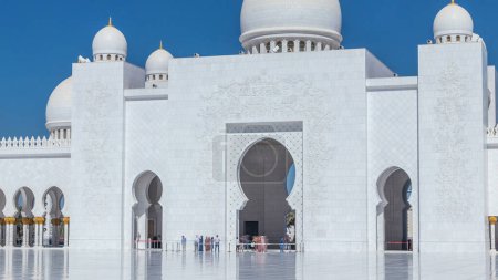 Foto de El timelapse de la Gran Mezquita Sheikh Zayed en Abu Dhabi, la capital de los Emiratos Árabes Unidos. Patio interior con entrada. Cielo azul en el día soleado - Imagen libre de derechos