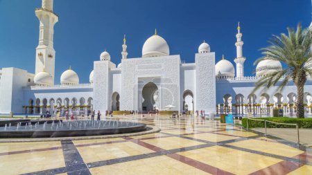 Foto de Sheikh Zayed Gran Mezquita timelapse hiperlapso en Abu Dhabi, la capital de los Emiratos Árabes Unidos. Vista frontal con fuentes. Cielo azul en el día soleado - Imagen libre de derechos