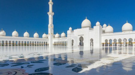 Photo for Sheikh Zayed Grand Mosque timelapse hyperlapse in Abu Dhabi. Inner court yard with shadows from minaret. Blue sky at sunny day - Royalty Free Image