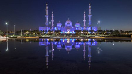 Téléchargez les photos : Grande mosquée Cheikh Zayed illuminée la nuit timelapse, Abu Dhabi, EAU. Vue du soir depuis Wahat Al Karama avec réflexions sur l'eau. La 3ème plus grande mosquée du monde - en image libre de droit
