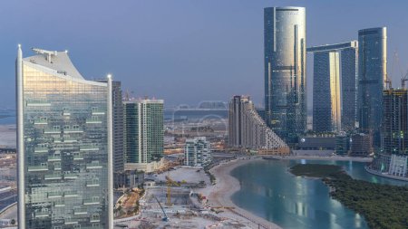 Photo for Skyscrapers on Al Reem Island in Abu Dhabi day to night transition timelapse after sunset from above. Aerial cityscape from Al Reem Island with illuminated buildings - Royalty Free Image